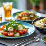 Prato com salada caprese e arroz biryani em uma mesa de madeira com copo de chá gelado ao lado.