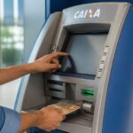 Pessoa realizando saque em caixa eletrônico da Caixa Econômica Federal.